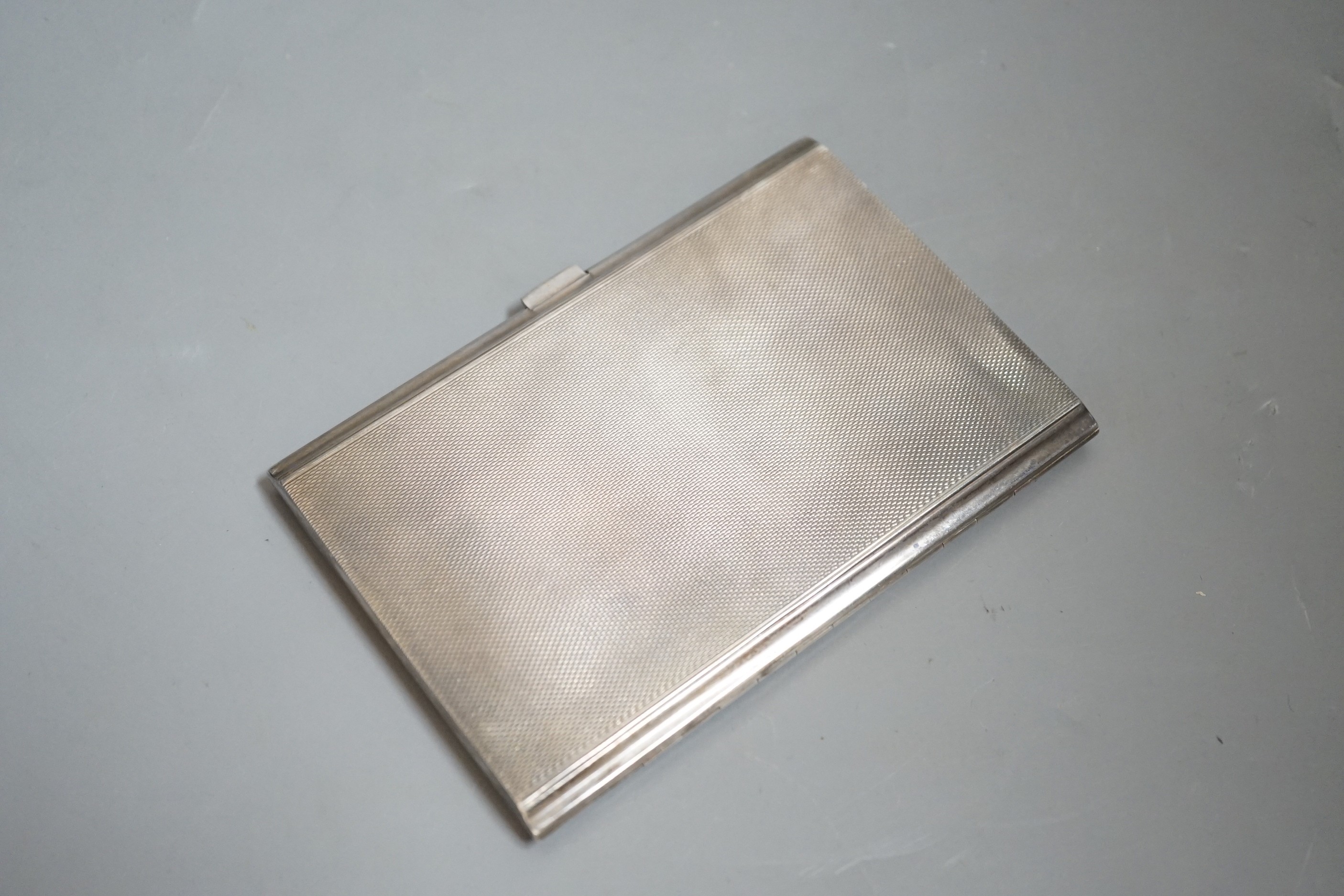 A George V engine turned silver rectangular cigarette case, 12.2cm, with engraved initials.